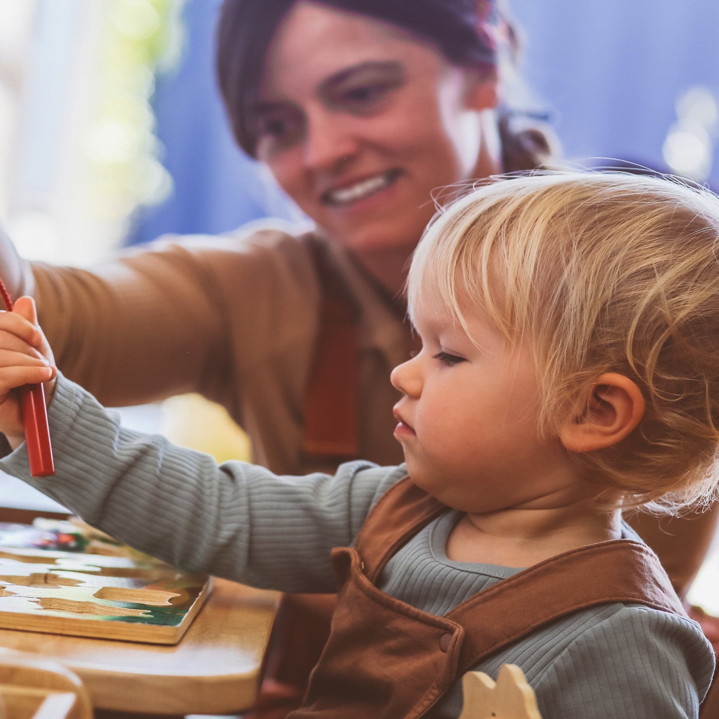 Child playing with a wooden toy while a woman watches in a cozy indoor setting